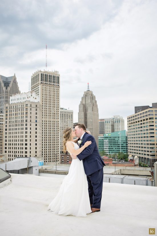 View from the Atheneum hotel rooftop in Detroit. Bride and groom kiss on the roof.